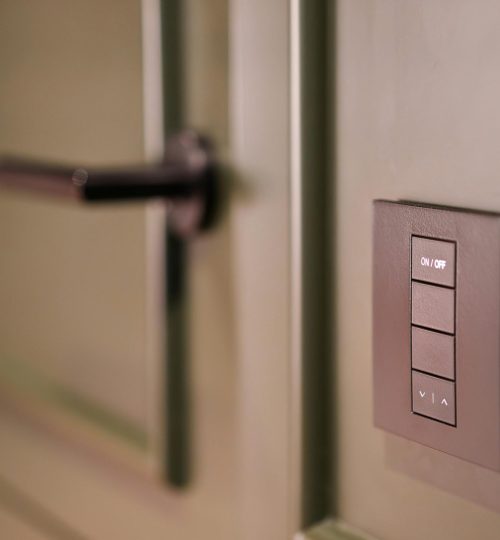 A smart light switch on a wall next to a modern door handle, emphasizing home automation.